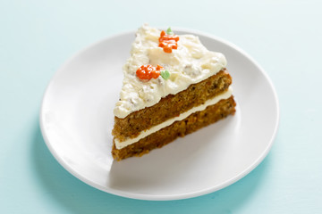 Fototapeta na wymiar Slice of carrot cake with frosting and carrot decoration. 