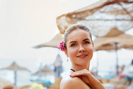  A Female  Applying Sun Cream Creme on  tanned  shoulder.Sun protection.Sun Protection, girl using sunscreen to safe her skin healthy.