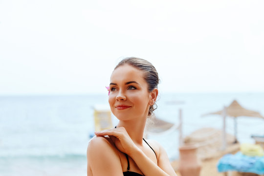 Beautiful woman on the beach and applying   Sun Cream spray on her body