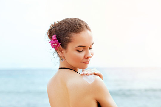 Woman applying sunscreen creme on  tanned  shoulder. Skincare. Body Sun protection sun cream. Bikini  woman smear  moisturizing lotion on back.