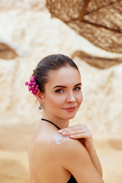 A Female  Applying Sun Cream Creme on  tanned  shoulder.Sun protection.Sun Protection, girl using sunscreen to safe her skin healthy.