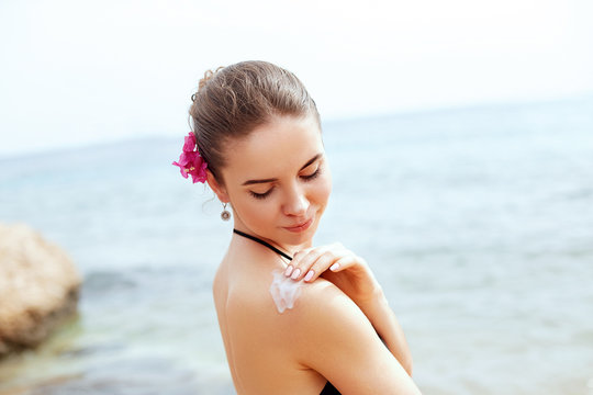 Woman applying sunscreen creme on  tanned  shoulder. Skincare. Body Sun protection sun cream. Bikini  woman smear  moisturizing lotion on back.