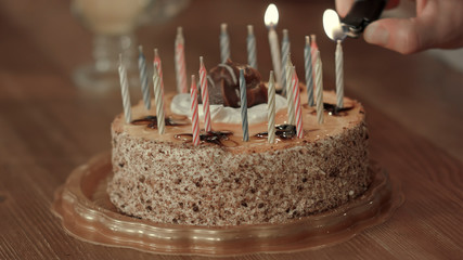 Male hand lighting candles in birthday cake