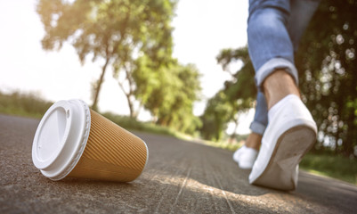 Mann wirft leeren Kaffeebecher weg.