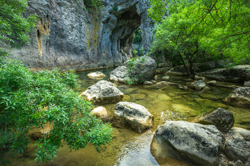 un décors avec une arche naturelle creusée dans la roche par une rivière 