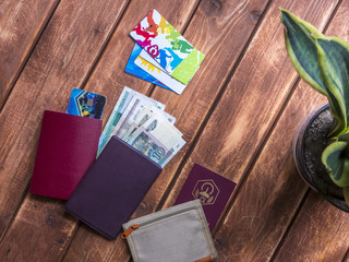 travel documents, wallet, cash and credit cards dropped on a wooden surface