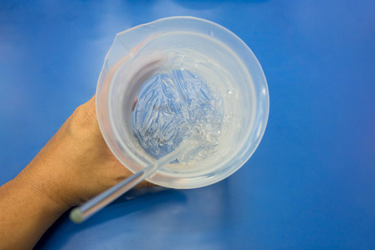 Hand Holding The Clear Solution With High Viscosity In Plastic Cup.