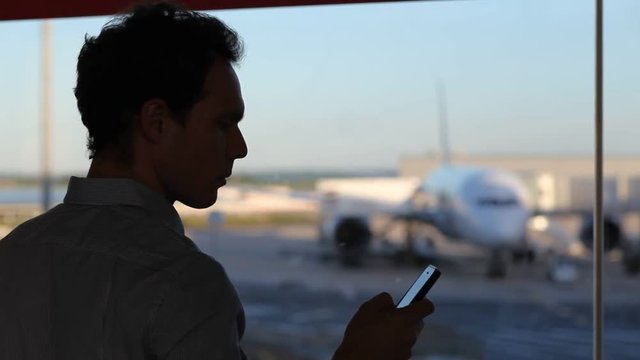 business travel, man with mobile phone texting or using internet on smartphone in airport