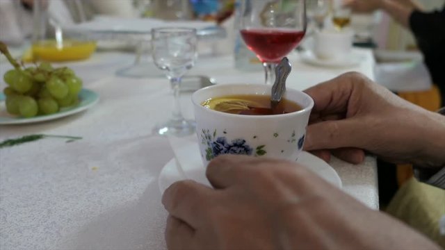 Man's Hands With Cup Of Tea On A Saucer With Sugar And Lemon