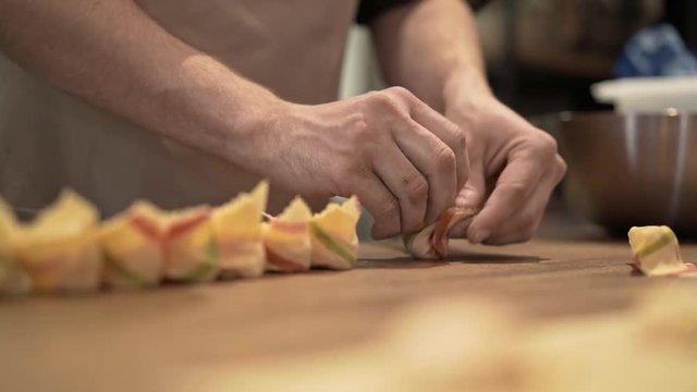 Hands of two unrecognizable middle age men making tortellini, a traditional Italian cuisine dish. Concept of a national tradition and agriculture. Locked down real time medium shot