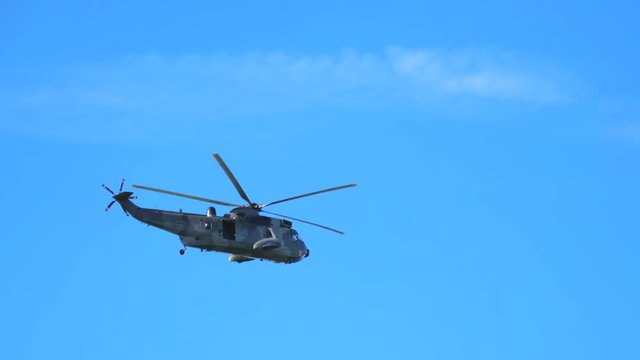 Military helicopter flying against blue sky. 4K.