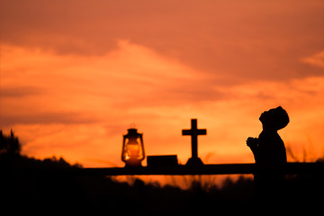 Boy praying with light sunset background.