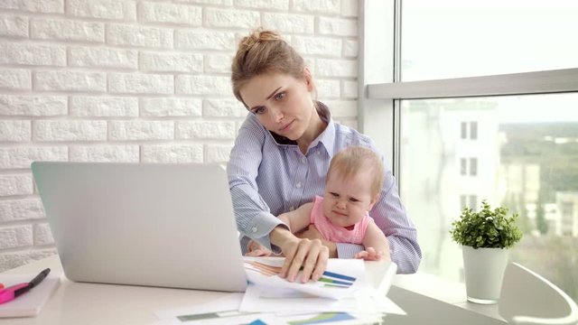 Baby distracted mother from conversation. Busy mom with child on hands speaking mobile phone. Working mother with baby at home. Modern woman working from home. Female employee with child girl