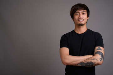 Young Asian man against gray background