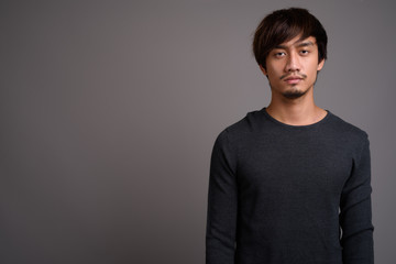 Young Asian man against gray background