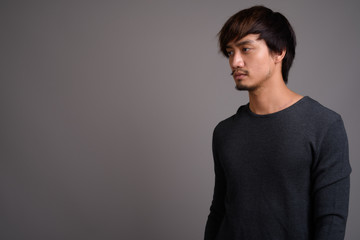 Fototapeta premium Young Asian man against gray background