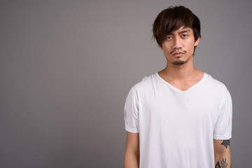 Young Asian man against gray background