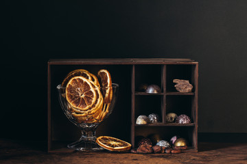 bowl with dry orange slices, nuts, chocolate candies and pieces on shelves