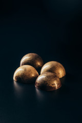 closeup image of chocolate candies with golden splashes on black background