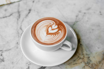 The hot coffee art in the white ceramic mug in the restaurant or coffee shop. 