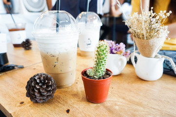Cool coffee, cactus and Pine cones on wooden table in the cafe.