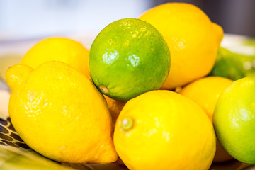 Several lemon and one lime in a bowl