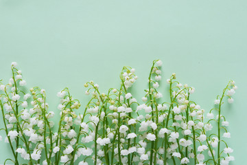 Romantic gentle flower background, lily of the valley on a mint color  background, top view, flat...