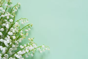 Foto auf Glas Romantischer sanfter Blumenhintergrund, Maiglöckchen auf mintfarbenem Hintergrund, Draufsicht, flaches Layout. © Tatiana Morozova