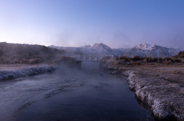 A small white bridge over a steaming hot creek near Sierra Nevada mountains in California