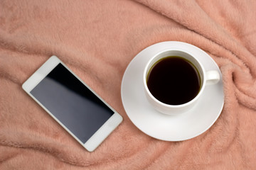 Fototapeta na wymiar top view coffee cup and cell phone on a pink blanket
