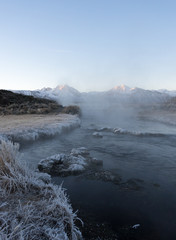 Fototapeta na wymiar Steam rising from the Hot Creek during a cold winter morning