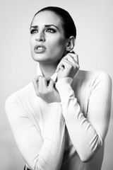 Young brunette woman wearing white poloneck in studio shot