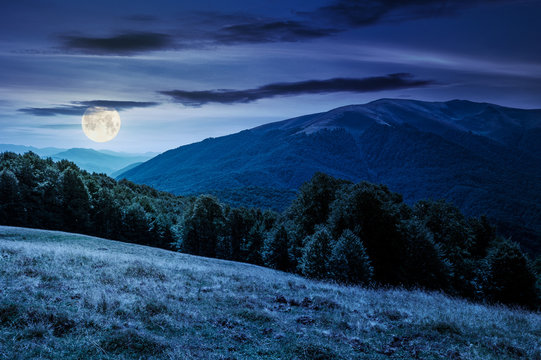 beautiful landscape of Carpathian mountains at night in full moon light. forested hills and Apetska mountain in the distance in summer
