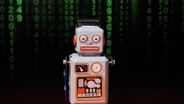 A neurotic tin toy robot standing in front of a distorted screen showing green numbers falling down (a popular sci-fi movie effect).

