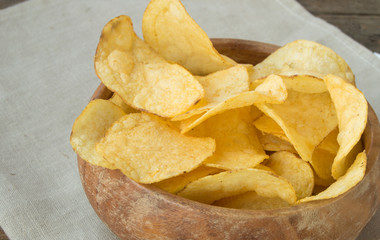 Delicious crispy potato chips in an old wooden bowl