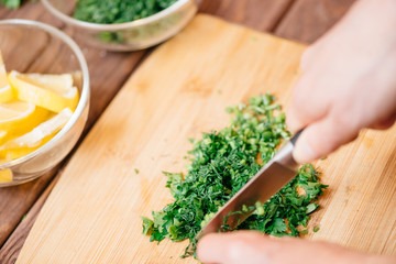 Woman cutting greenery on wooden board.