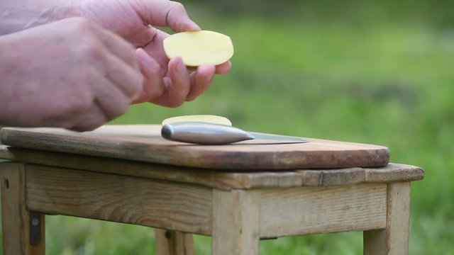 Men's hands cut potatoes in nature in summer