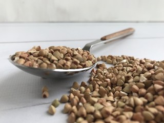 low angle closeup of buckwheat grains spilling out of silver spoon
