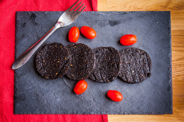 Black pudding and cherry tomatoes on a slate plate
