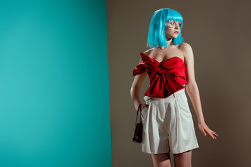 beautiful fashionable female model in blue wig posing and looking away in studio