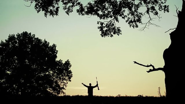 The hunter rejoices in the good fortune. Hands with a gun raised up