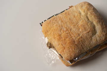 Fresh tasty panini sandwich with plastic waste and paper cardboard inside on white background. Recycled waste in our food concept