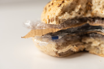 Fresh tasty cut out burger panini with plastic waste and paper cardboard inside on white background. Recycled waste in our food concept