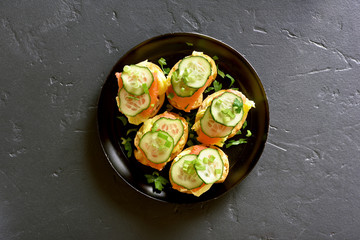 Sandwiches with salmon, scrambled eggs and cucumber
