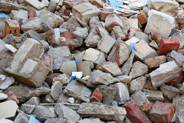 Pile of construction waste grey concrete pieces and old broken bricks lying on construction site as...
