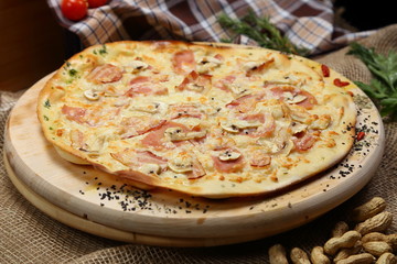 Pizza thin with sausage, mushrooms, cheese, spices, a glass of juice, tomatoes, nuts