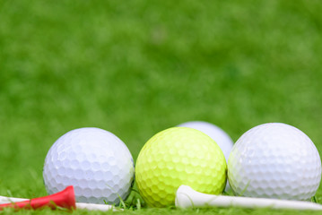 Close up golf ball and tee on green grass field background.