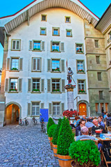 People at sidewalk cafe near Banneret fountain in Rathausplatz Bern