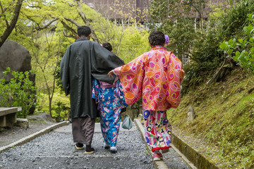 Japanese family in traditional clothes walking in Kyoto park, Japan