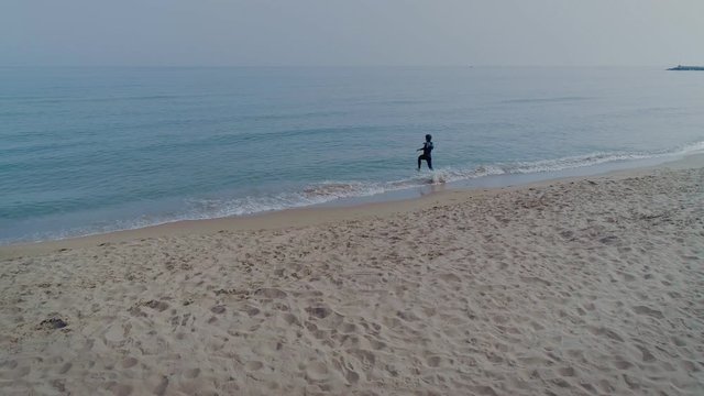 Athletic man or professional sportsman in wetsuit, runs into ice cold clear water during sunrise morning training, swims in breast stroke style, healthy lifestyle of active modern person